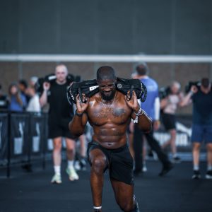DFWS personal trainer doet lunges met zandzak tijdens Hyrox-wedstrijd
